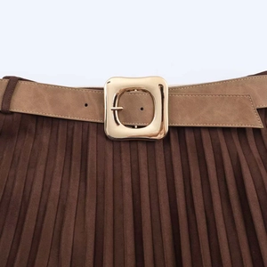 Detail of dark brown pleated skirt featuring a faux suede texture and large gold belt buckle