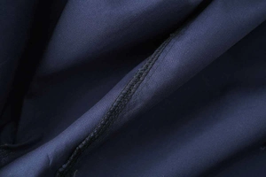 Detail of dark blue cotton poplin fabric showing precise stitching and smooth texture
