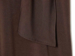 Detailed close-up of brown woven fabric with precise stitching on dress pocket flap