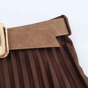 Detail of pleated dark brown midi skirt featuring a suede texture and gold buckle belt
