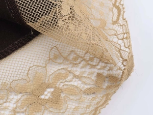 Macro detail of dark brown satin fabric with golden floral lace embroidery stitching