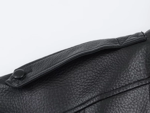 Detailed close-up of high-quality black lychee texture leather jacket shoulder and button