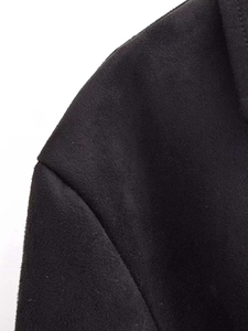 Dettaglio ravvicinato della trama in velluto e della cucitura sulla spalla del blazer nero