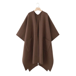 Detail view of large symmetrical pockets and high-density wool fabric on brown poncho coat