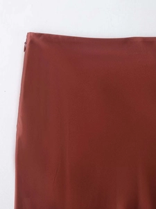 Detail of rust red satin midi skirt showing waist stitching and invisible zipper closure