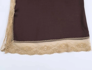 Detailed view of dark brown satin hem with intricate gold floral lace and wavy edges