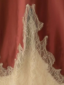 Detail of elegant burgundy satin fabric with vintage cream lace stitching and texture