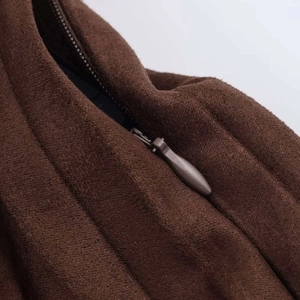 Detailed close-up of dark brown pleated skirt featuring a hidden zipper and soft texture