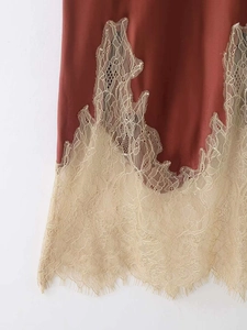 Detail of brick red satin skirt featuring delicate beige eyelash lace contrast trim