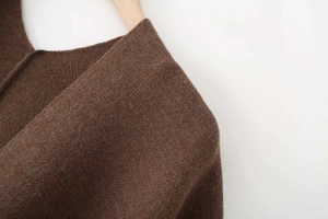 Close-up of a brown knit V-neck poncho top showing the fine fabric texture and drape