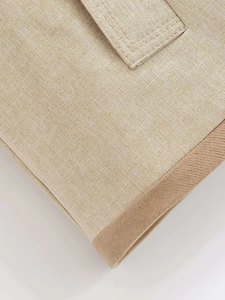 Detail shot of beige linen fabric texture with precision stitching and brown piping trim