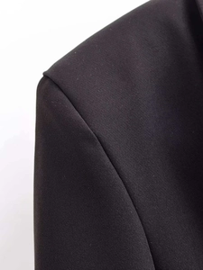 Detailed macro view of the shoulder seam and black twill fabric texture on a slim suit jacket