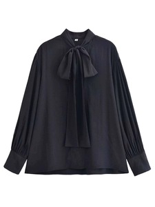 Close-up of black V-neck blouse with bow tie collar and pleated long lantern sleeves