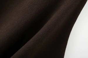 Detailaufnahme der weichen dunkelbraunen Strickstruktur für herbstliche Damenponchos