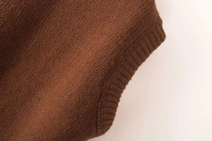 Close-up of brown knit vest showing detailed ribbed hem and fine texture on high neck top