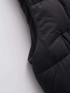 Close-up of black quilted puffer vest showing detailed stitching and armhole seam
