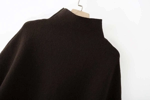 Detailansicht des dicken Strickstoffs und des hohen Kragens am schwarzen Poncho