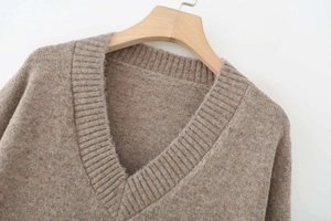 Close-up of ribbed V-neckline on soft beige oversized knit sweater for women