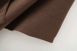Close-up of premium dark brown knitted fabric texture for autumn loose poncho coat