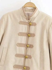 Close-up of beige linen blazer featuring vintage gold buttons and stand collar