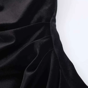 Détail du plissé en velours noir lustré sur une robe à la coupe asymétrique