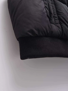 Close-up of black quilted vest featuring wide elastic ribbed hem and windproof fabric