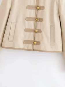 Detailed macro view of woven oatmeal texture jacket with bronze buckles and contrast piping