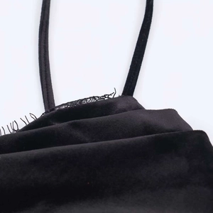 Détail macro du tissu en velours noir et de la fine bretelle d'une robe élégante