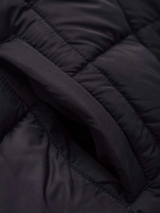 Detailed close-up of the black quilted vest featuring lateral pocket and smooth stitching