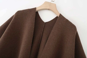 Close-up of deep brown V-neck poncho knitwear texture and stitching details
