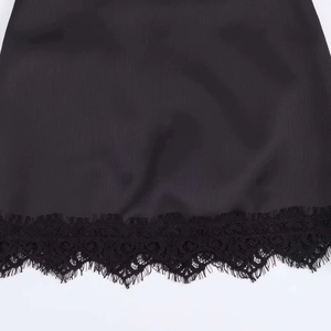 Close-up of black silky fabric featuring intricate floral eyelash lace trim on the hem