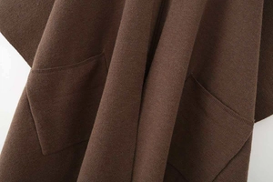 Detailed texture of thick dark brown knit poncho jacket with symmetric hand pockets