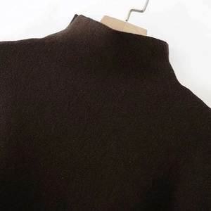 Nahaufnahme eines dunkelbraunen Strickponchos mit Rollkragen und feiner, warmer Textur