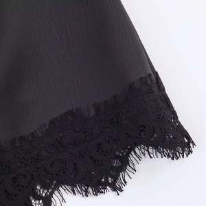 Detail of black skirt hem showing delicate eyelash lace trim and textured chiffon fabric