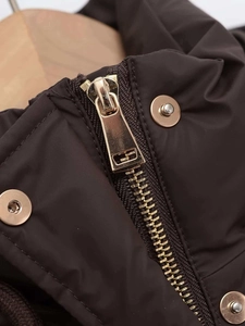 Close-up of golden metal zipper and snap button on dark brown hooded winter parka jacket