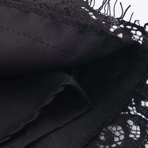 Close-up of black lace fabric details with hollow-out patterns and scalloped hemline