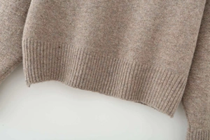 Macro shot of oatmeal melange knitted sweater featuring a classic ribbed hem detail