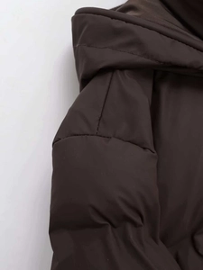 Detail view of deep brown hooded puffer jacket shoulder seam and matte fabric texture