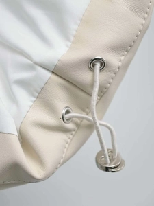 Macro detail of white faux leather vest featuring silver eyelets and drawstring adjustment