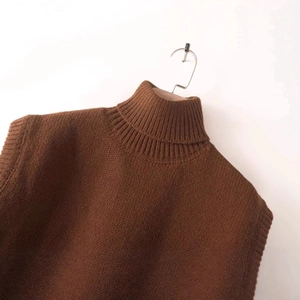 Dark brown sleeveless knit vest with ribbed high neck collar on wooden hanger