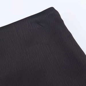 Detailed macro view of black pleated fabric with vertical texture and ruffled hemline edge