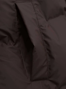 Detailed close-up of side pocket stitching and quilted texture on a long hooded parka coat