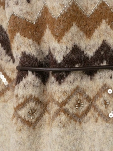Macro view of jacquard knit texture with shimmering sequins and beads on a stylish cardigan