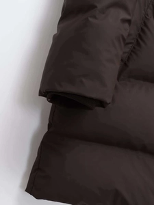 Close-up of windproof ribbed knit cuffs on dark brown hooded long quilted coat