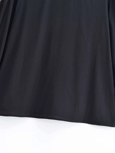 Detailed macro view of the finely stitched hem on a lightweight black chiffon shirt fabric