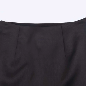 Detailed view of black pleated waist on textured crepe skirt with precise darts