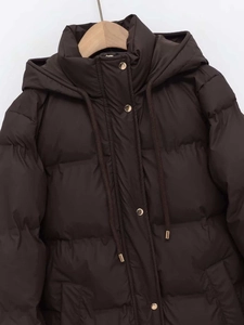 Detail of dark brown hooded puffer coat featuring golden metal snaps and zipper closure