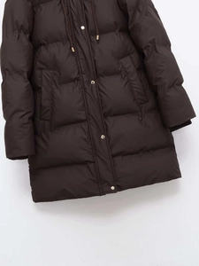 Detail of dark brown quilted parka featuring gold metal snap buttons and drawstring hood