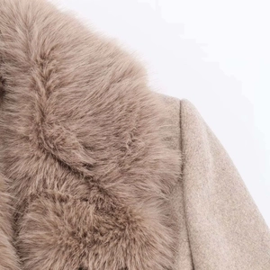 Detailed close-up of fluffy faux fur collar and textured wool coat in light camel beige