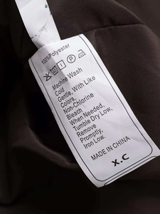 Detail view of the 100% polyester fabric care label on a winter hooded puffer coat
